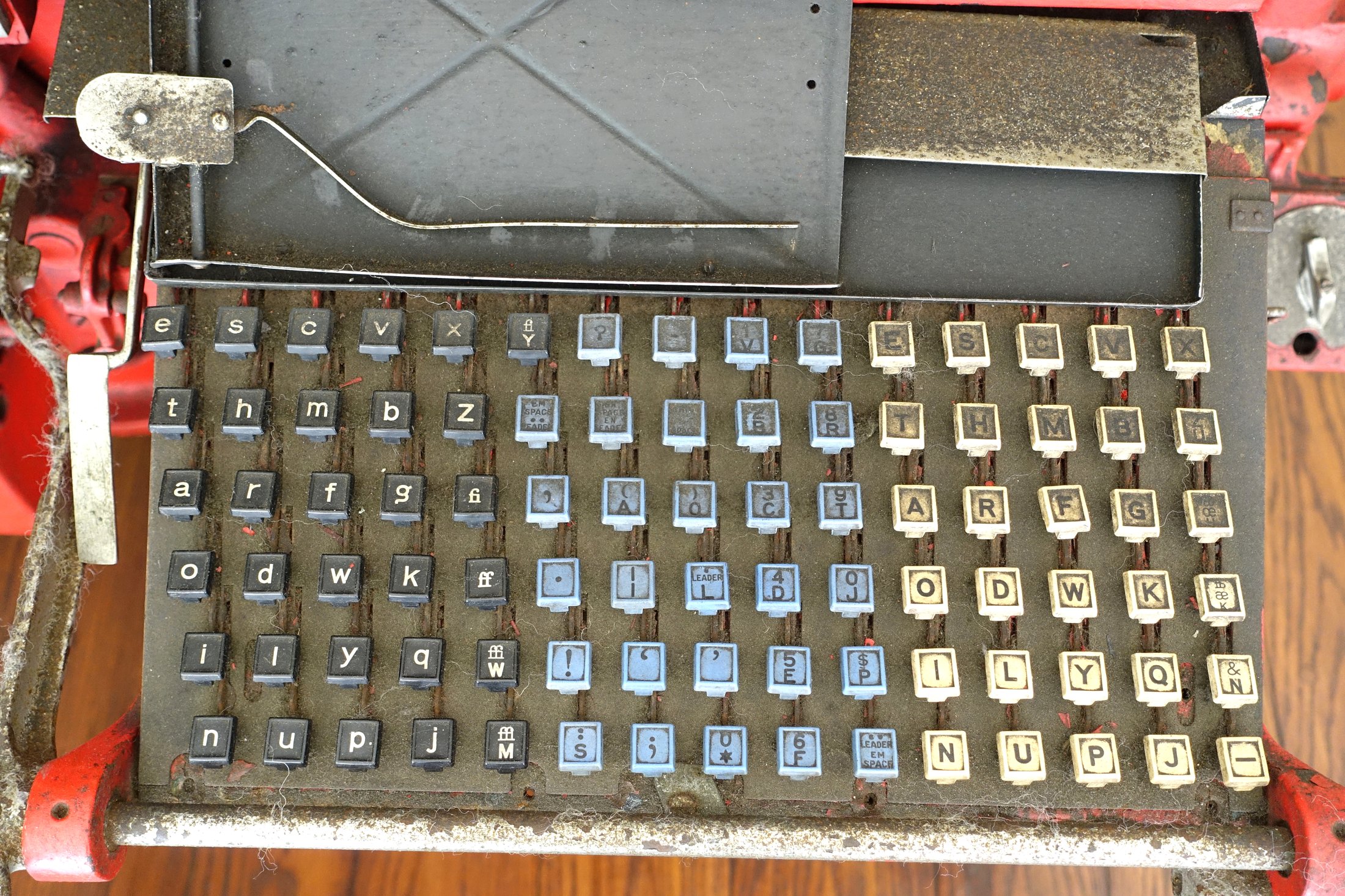 The brass and black keyboard of a Mergenthaler Linotype typesetting machine, with round white key caps in a curved three-tier arrangement, photographed close up.